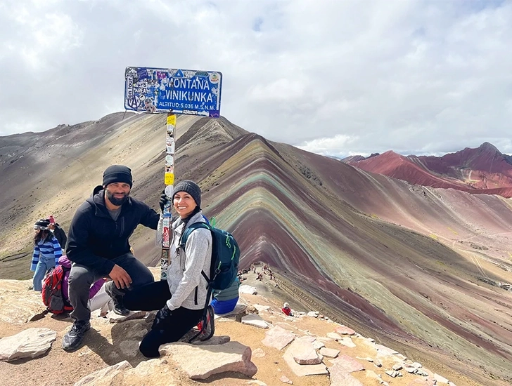 Pareja en el mirador de la Montaña de Colores rodeada de colinas multicolores en Cusco, Perú