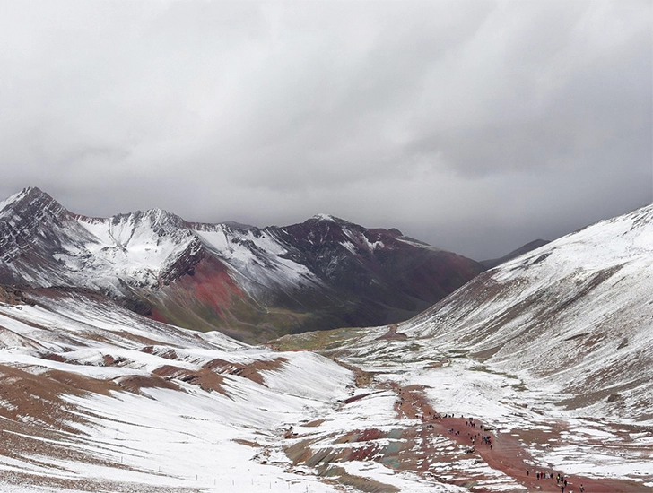 Snow-covered Rainbow Mountain, also known as Vinicunca, showcasing colorful mineral layers and white Andean peaks in Cusco, Peru